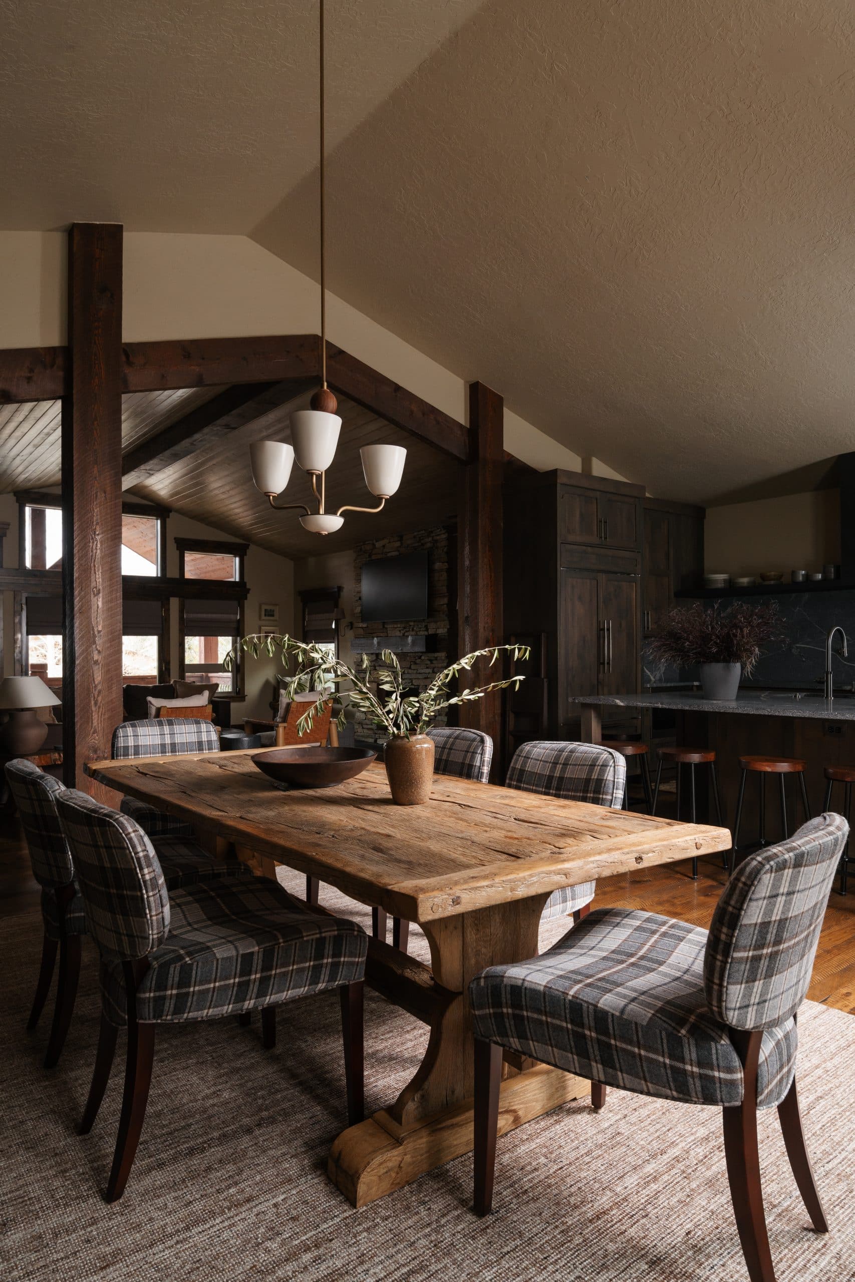 Mountain modern dining room in Park City home featuring reclaimed wood table, plaid chairs, and exposed timber beams
